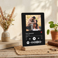 Black acrylic photo frame on wooden stand with couple photo and music waveform icons