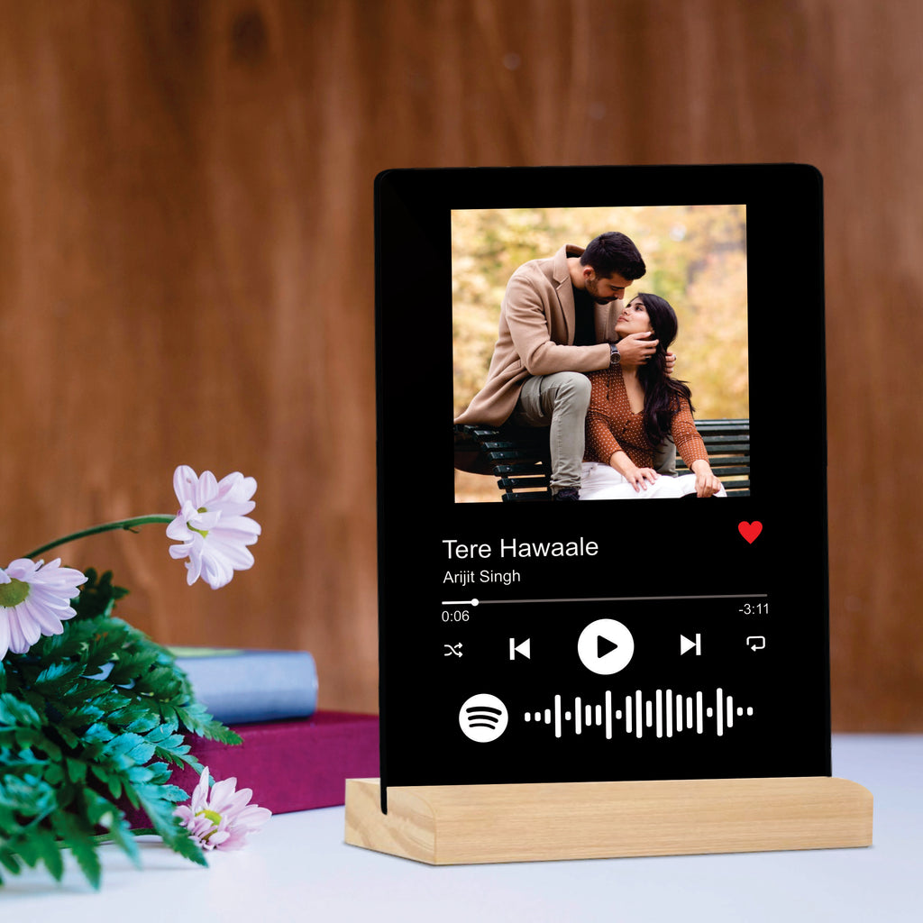 Black acrylic photo frame on wooden stand with couple photo and playback controls