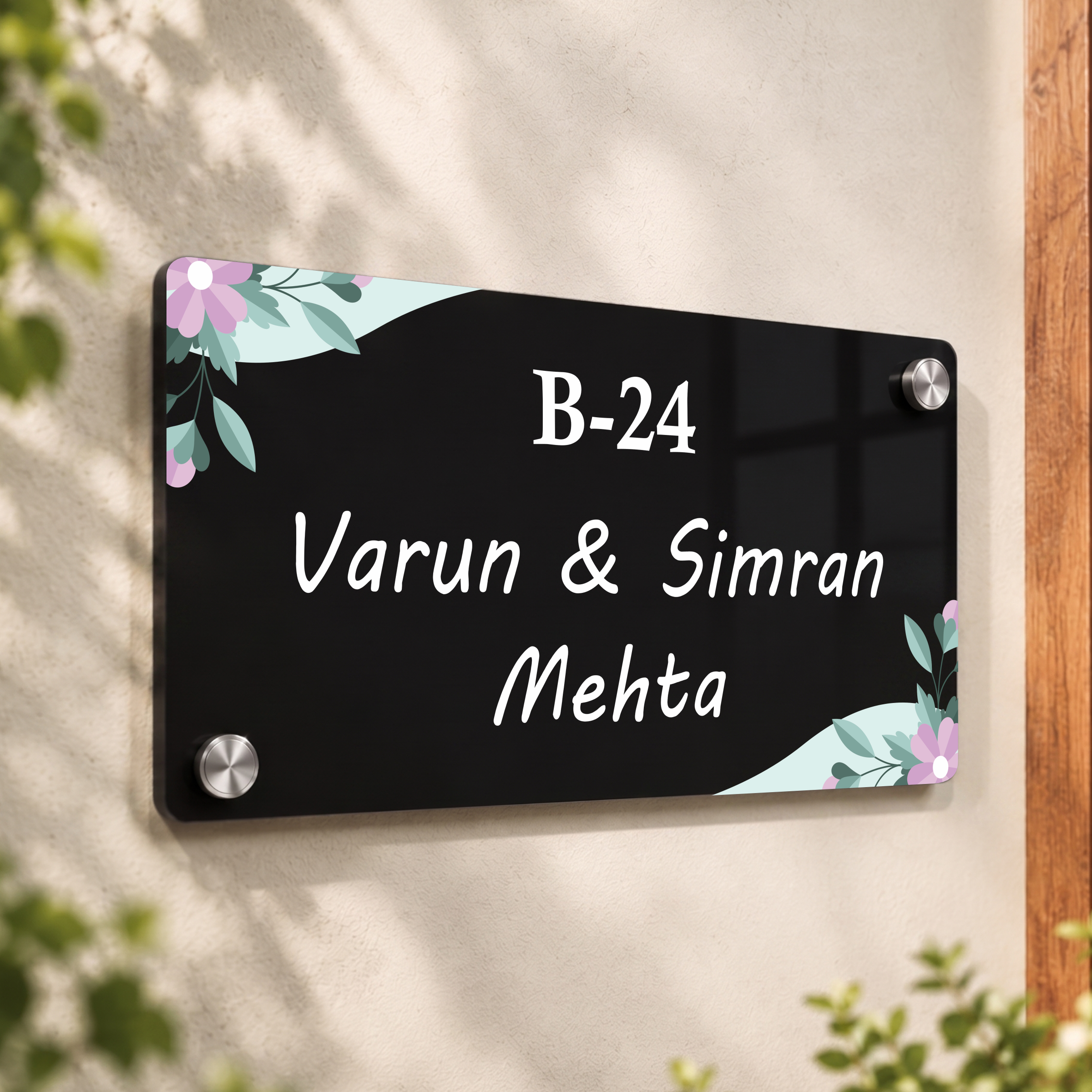 Black acrylic door name plate with floral corners, B-24 and Varun & Simran Mehta.