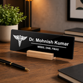 Black acrylic desk name plate with white text, caduceus logo, and wooden stand