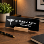 Black acrylic desk name plate with white text, caduceus logo, and wooden stand