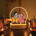 Glowing LED devotional lamp with arch showing dancing Krishna and Radha figures