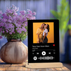 Black acrylic photo frame on wooden stand with couple photo and playback icons
