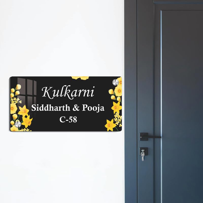 Black acrylic door name plate with yellow flower border, mounted on a dark door