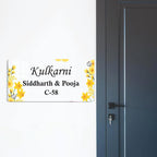 Transparent acrylic door name plate with yellow floral accents and metal mounting corners