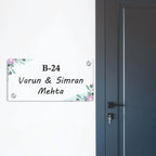 Transparent acrylic door name plate with pastel floral corners, text B-24 Varun & Simran Mehta