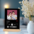 Black acrylic photo frame on wooden stand with couple photo and Spotify-style icons