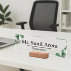 Clear acrylic name plate with green leaf print, engraved name and designation on wood stand