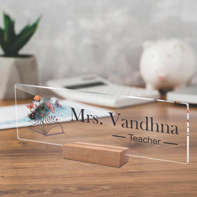 Transparent acrylic name plate, Mrs. Vandhna and Teacher text with floral book illustration.