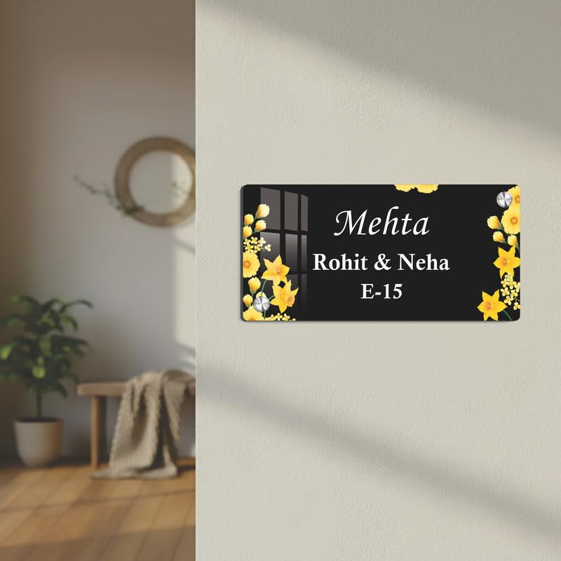 Black acrylic door name plate with yellow flower border on an off-white wall