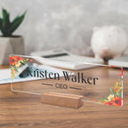 Transparent acrylic desk name plate, floral border, engraved name and CEO, on wooden stand