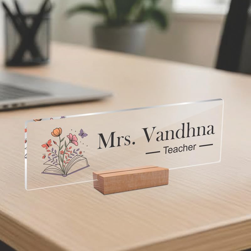 Transparent acrylic desk name plate with Mrs. Vandhna, Teacher text and open-book floral art.