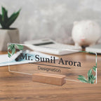 Clear acrylic name plate with green leaf corners, engraved name and designation on wood stand
