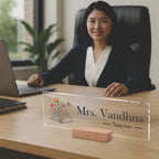 Transparent acrylic name plate on a wooden stand with Mrs. Vandhna and Teacher text.