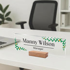 Transparent acrylic desk name plate: Manny Wilson, manager, leaf border; wooden stand