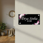 Black door name plate with pink floral corners and name "Diya Sinha" D-105
