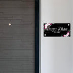 Black door name plate with pink floral corners and name "Inaya Khan" E-108