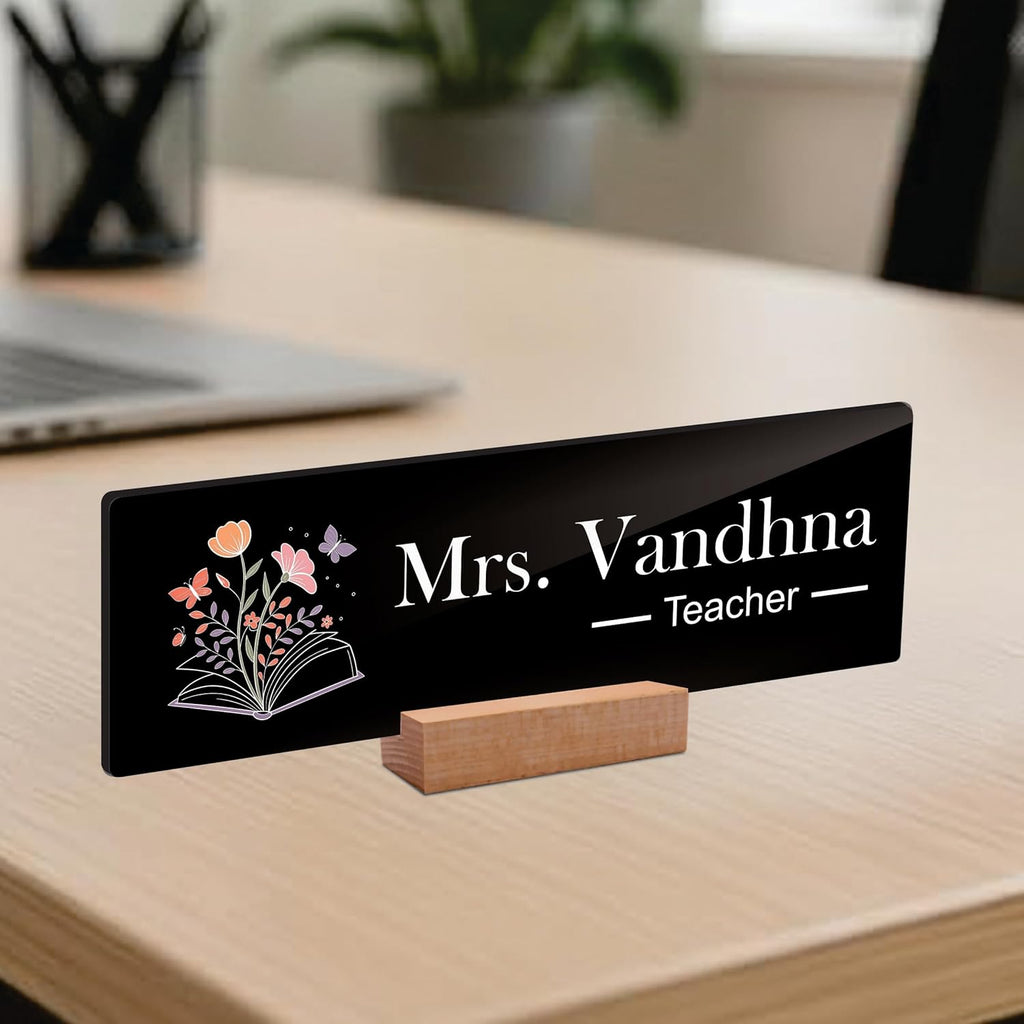 Black acrylic desk name plate: Mrs. Vandhna Teacher with floral book icon and wooden stand