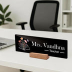 Black acrylic desk name plate, Mrs. Vandhna Teacher with floral book icon and wooden base