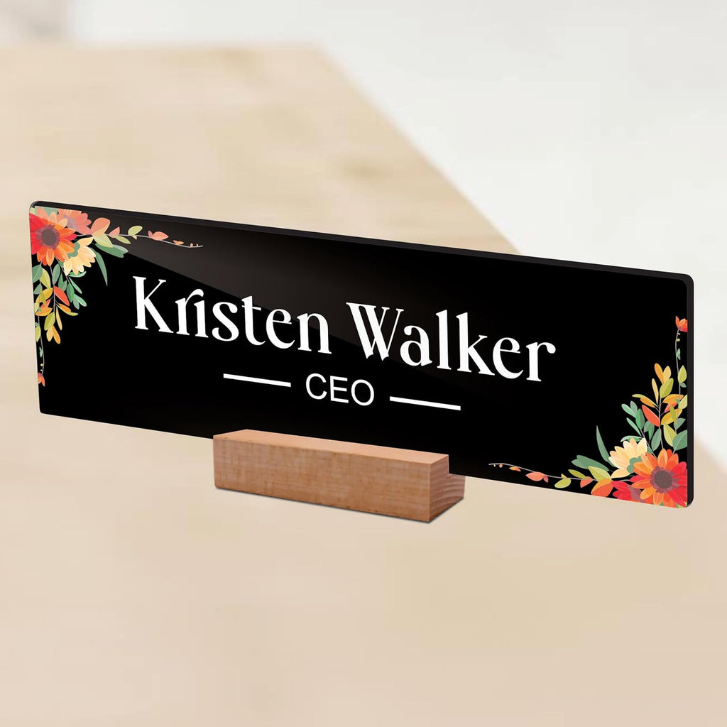 Black acrylic desk name plate with floral border, 'Kristen Walker' and CEO on wooden stand