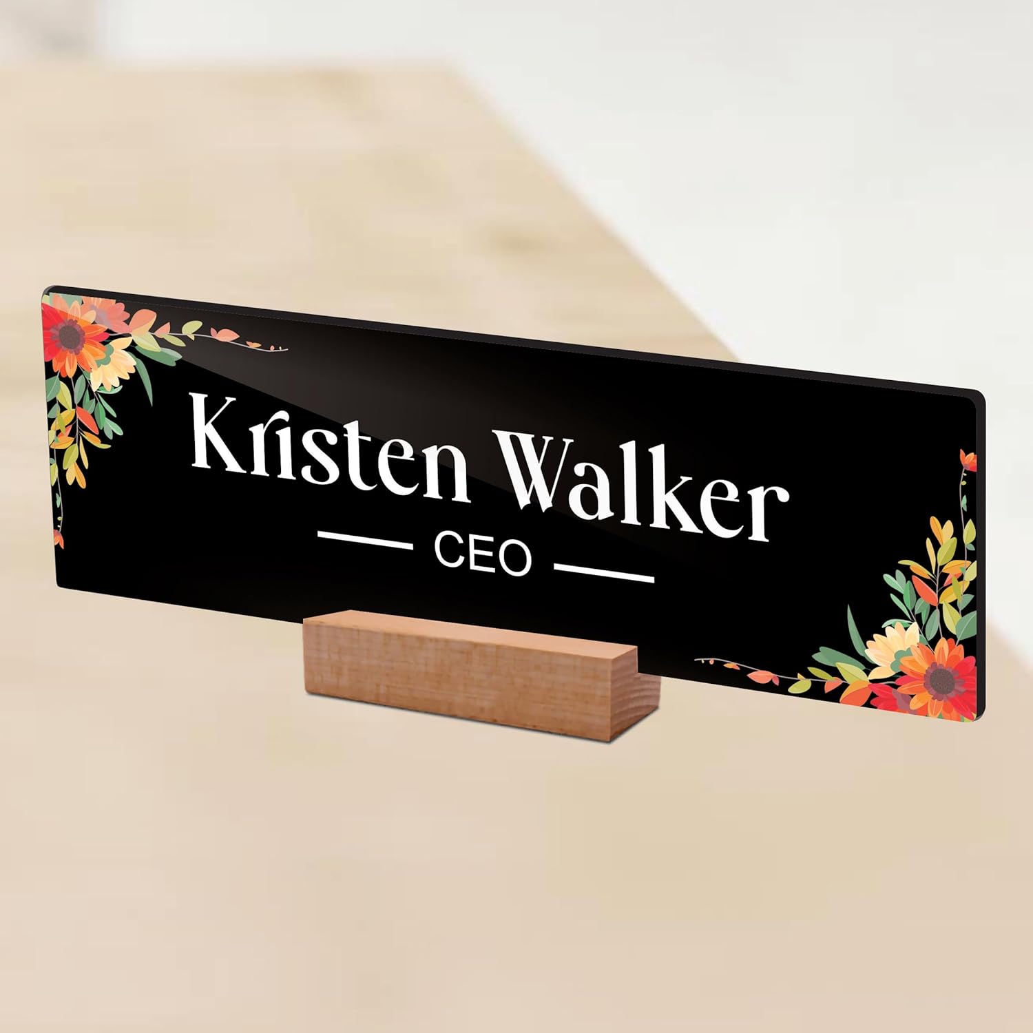 Black acrylic desk name plate with floral border, 'Kristen Walker' and CEO on wooden stand