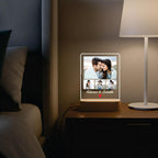 LED acrylic photo frame on wood base with warm glow, bedside-style view and heart