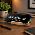Black acrylic desk name plate with floral border, 'Kristen Walker' and CEO on wooden stand